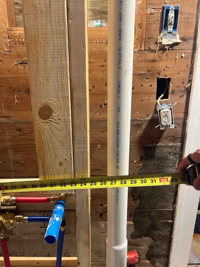 Plumber measuring water supply piping ahead of a water heater installation in Stephenville, TX